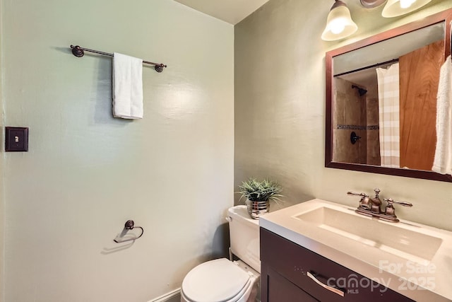 bathroom featuring toilet, vanity, and a shower