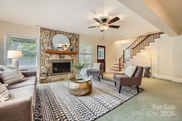 carpeted living area with visible vents, baseboards, ceiling fan, stairway, and a fireplace