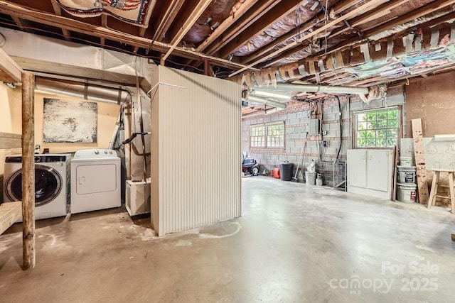 below grade area featuring concrete block wall, electric panel, and washing machine and clothes dryer