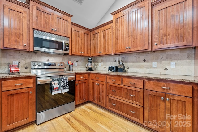 1263 Waterford Dr, Hickory, NC 28602 - kitchen with appliances with stainless steel finishes, lofted ceiling, brown cabinetry, light wood-style floors, and backsplash
