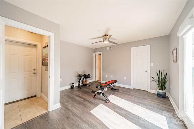 exercise area with visible vents, baseboards, wood finished floors, and a ceiling fan