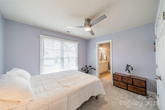bedroom featuring visible vents, a ceiling fan, ensuite bath, baseboards, and light colored carpet