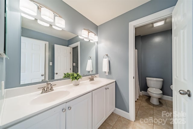 bathroom with a sink, baseboards, toilet, and tile patterned floors