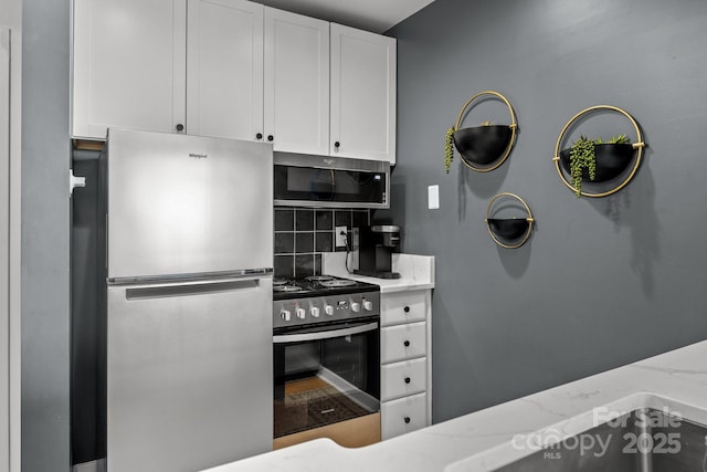 715 N Church St Unit 503, Charlotte, NC 28202 - kitchen featuring decorative backsplash, appliances with stainless steel finishes, white cabinetry, and light stone countertops