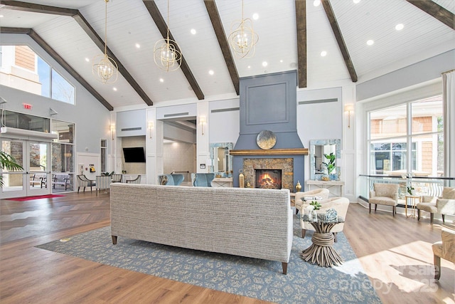 living room with beamed ceiling, high vaulted ceiling, a notable chandelier, and a fireplace