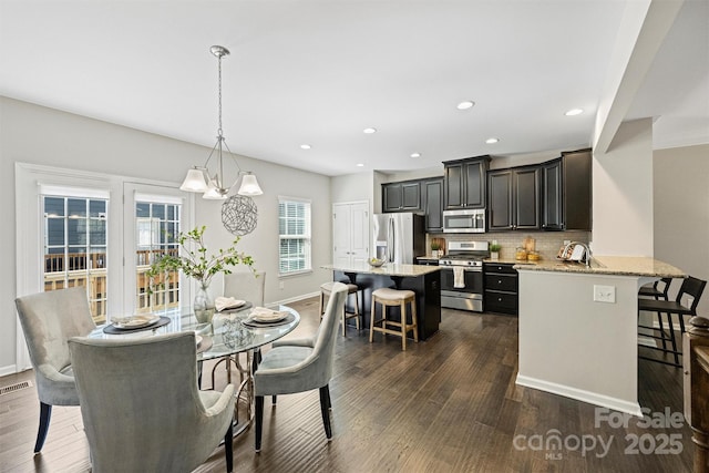 dining area with a notable chandelier, recessed lighting, dark wood-style floors, and baseboards