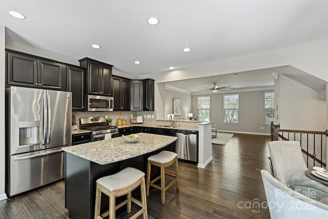 kitchen featuring backsplash, a center island, open floor plan, appliances with stainless steel finishes, and a peninsula