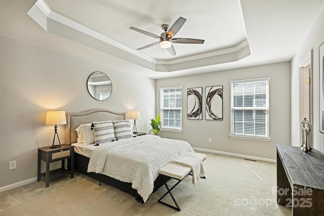 carpeted bedroom with a ceiling fan, a tray ceiling, crown molding, and baseboards