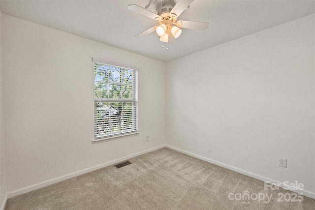 empty room with visible vents, light carpet, baseboards, and ceiling fan