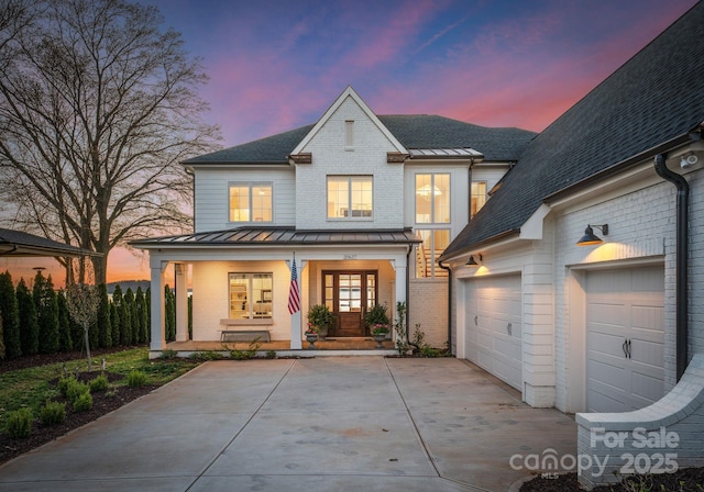 view of front facade with a porch, a standing seam roof, brick siding, and concrete driveway