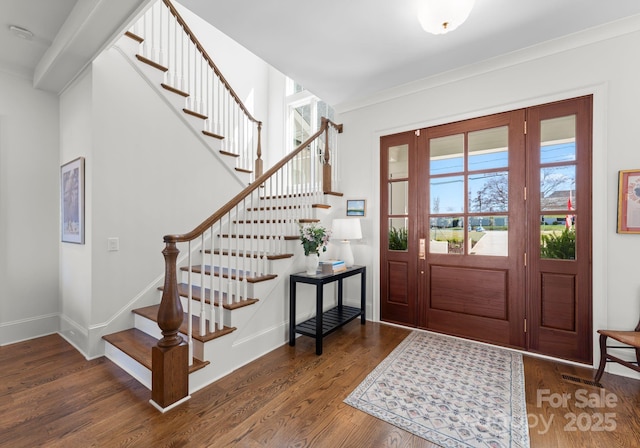 foyer featuring baseboards, wood finished floors, and stairway