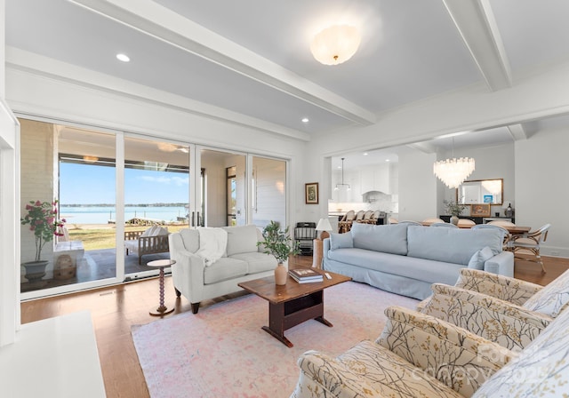 living room featuring a chandelier, a water view, beamed ceiling, light wood-style flooring, and recessed lighting