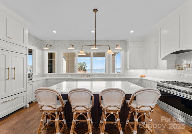 kitchen featuring white cabinetry, a sink, backsplash, and range with two ovens