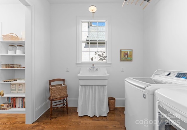 washroom with washing machine and dryer, wood finished floors, baseboards, and laundry area