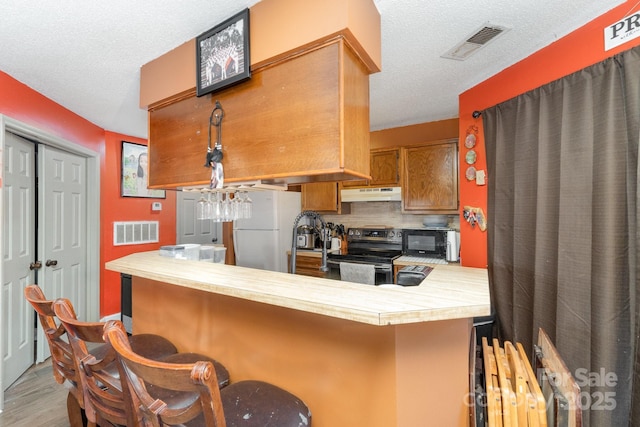 8175 Cedar Glen Dr, Charlotte, NC 28212 - kitchen featuring visible vents, under cabinet range hood, stainless steel electric stove, light countertops, and freestanding refrigerator