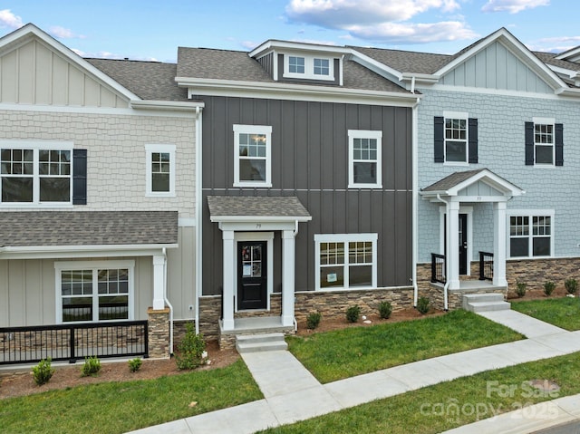 view of front of house with board and batten siding, stone siding, and roof with shingles