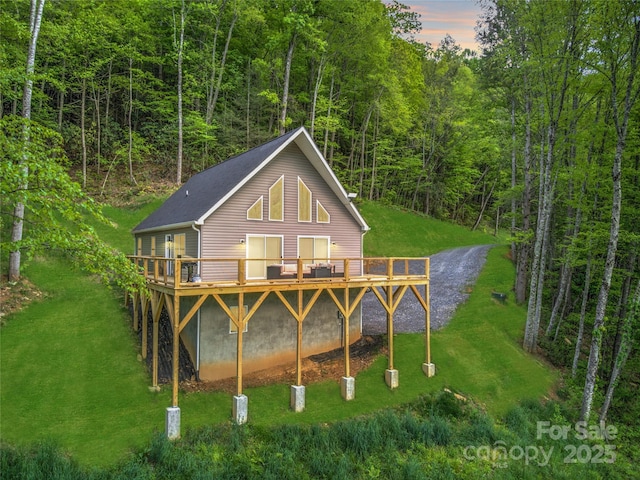 145 Banjo Ln, Waynesville, NC 28785 - back of property at dusk with a wooden deck, a yard, and a view of trees
