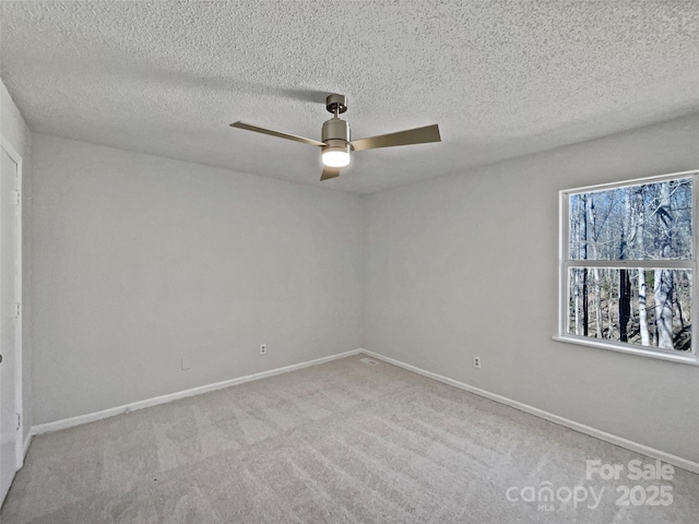 empty room with a textured ceiling, baseboards, carpet, and ceiling fan