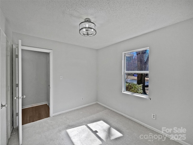 unfurnished bedroom with a notable chandelier, carpet, baseboards, and a textured ceiling
