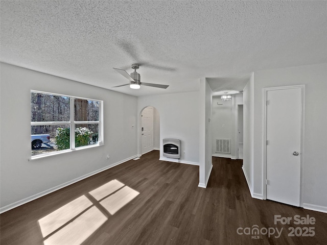 unfurnished living room featuring visible vents, heating unit, wood finished floors, arched walkways, and baseboards