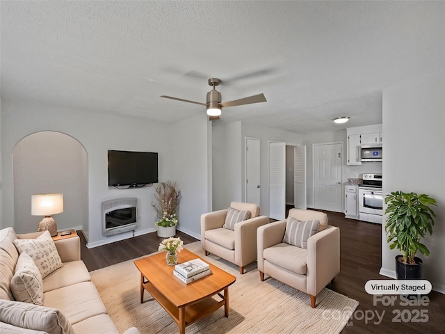 living area featuring ceiling fan, heating unit, wood finished floors, and a textured ceiling