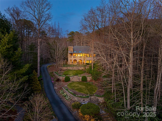 exterior space featuring a balcony, a forest view, and a chimney