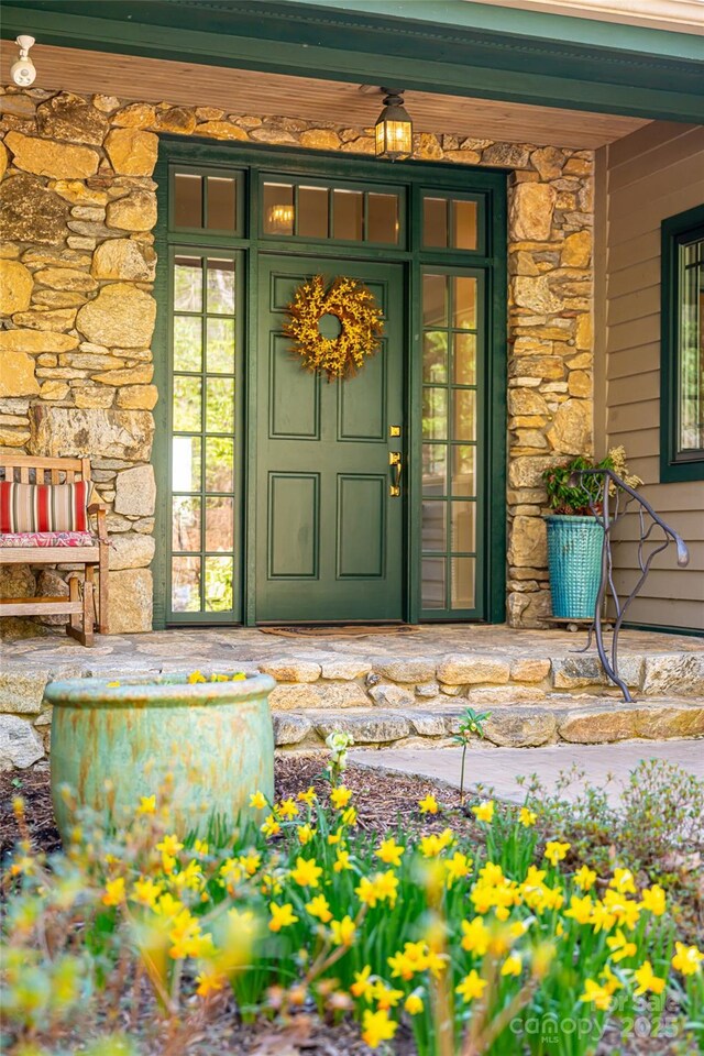 doorway to property featuring a porch and stone siding