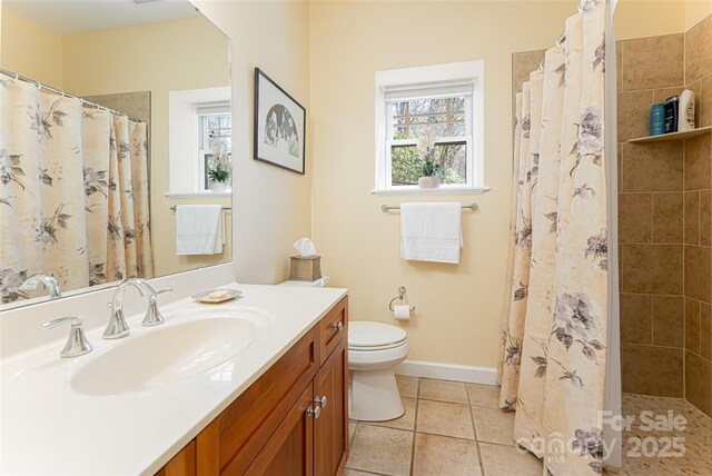 full bath with vanity, a tile shower, toilet, baseboards, and tile patterned floors
