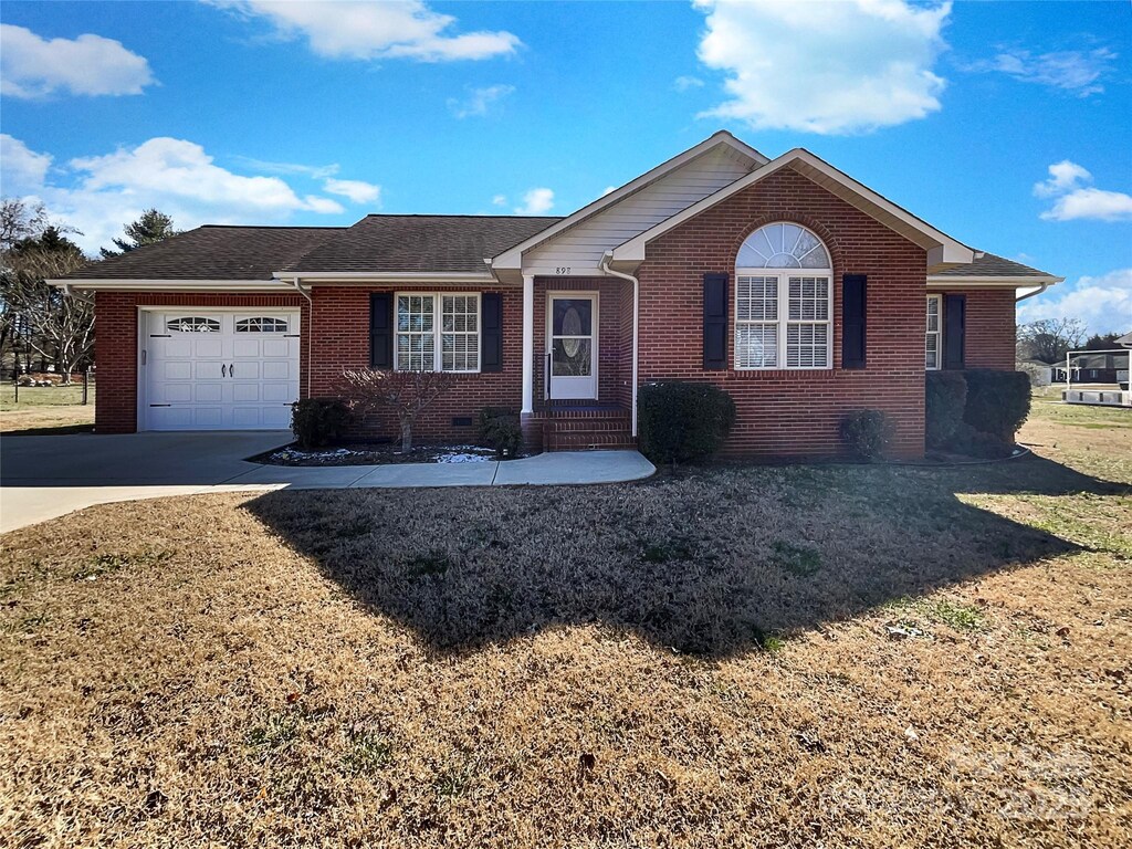 ranch-style house featuring a front lawn, brick siding, concrete driveway, and an attached garage