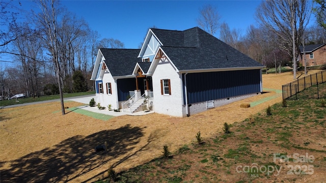 view of side of property with driveway, fence, a shingled roof, crawl space, and brick siding