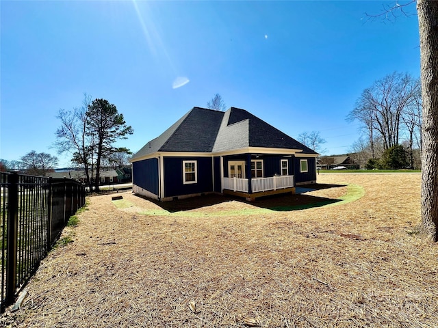 back of house with a lawn, a shingled roof, and fence