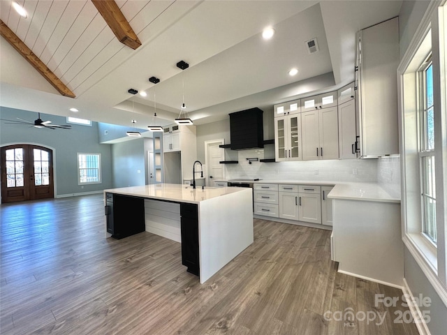 kitchen with light wood-type flooring, visible vents, a ceiling fan, tasteful backsplash, and light countertops