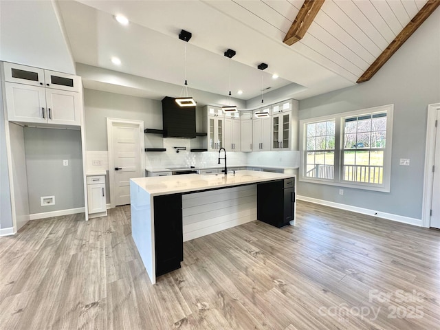 kitchen with decorative backsplash, light wood-style flooring, baseboards, and a sink