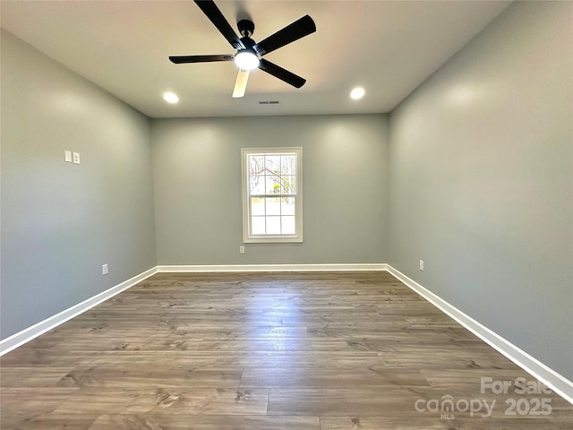 empty room featuring a ceiling fan, visible vents, wood finished floors, and baseboards
