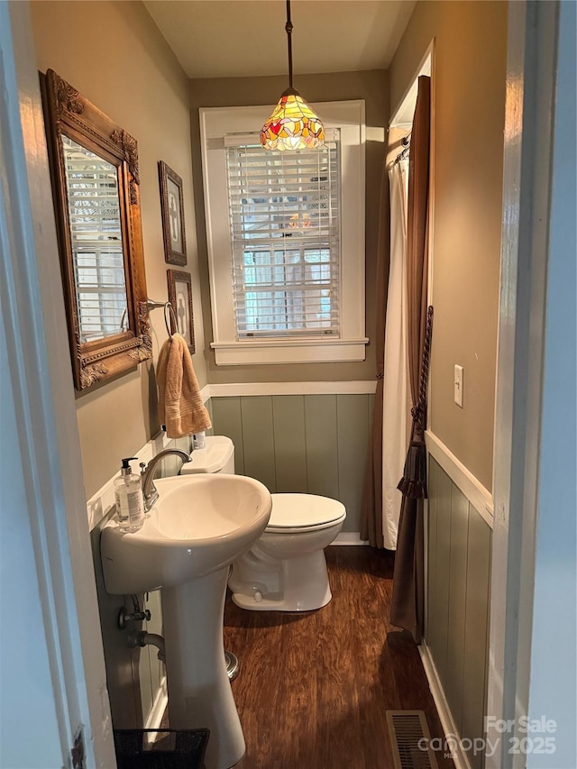 bathroom featuring wood finished floors, visible vents, toilet, and wainscoting