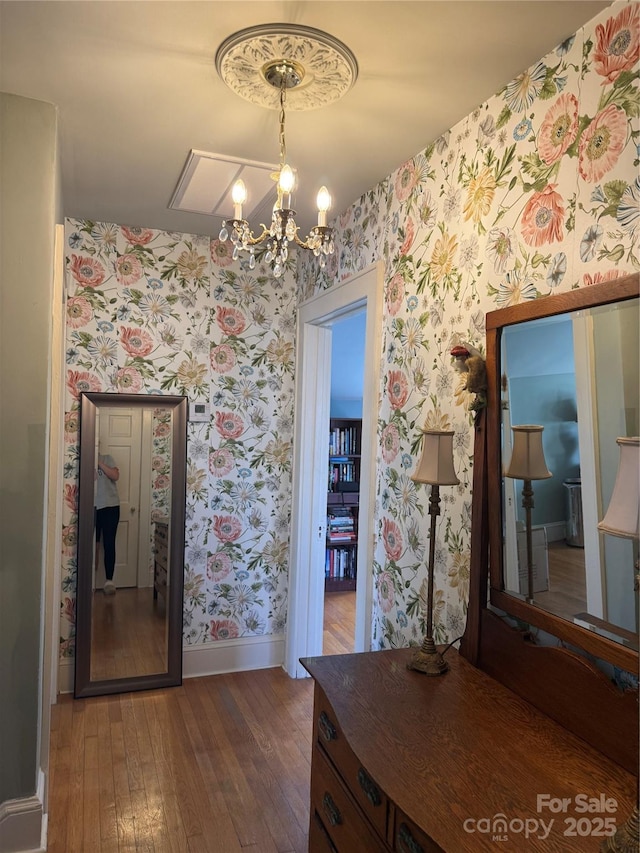 interior space with baseboards, wallpapered walls, a notable chandelier, and wood-type flooring
