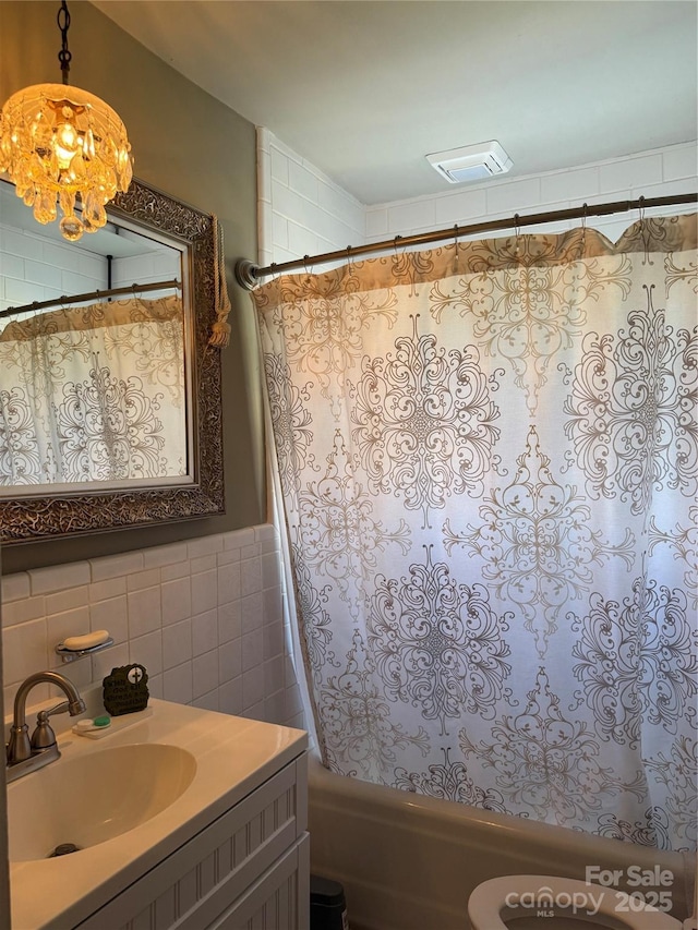 bathroom featuring tile walls, visible vents, vanity, shower / tub combo with curtain, and a notable chandelier