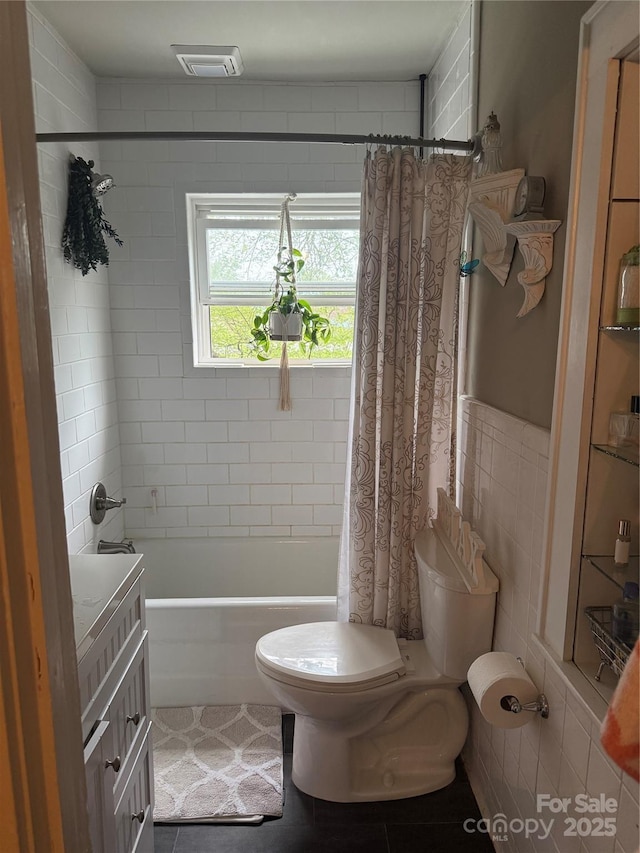 full bath featuring toilet, shower / bathtub combination with curtain, tile patterned flooring, visible vents, and tile walls