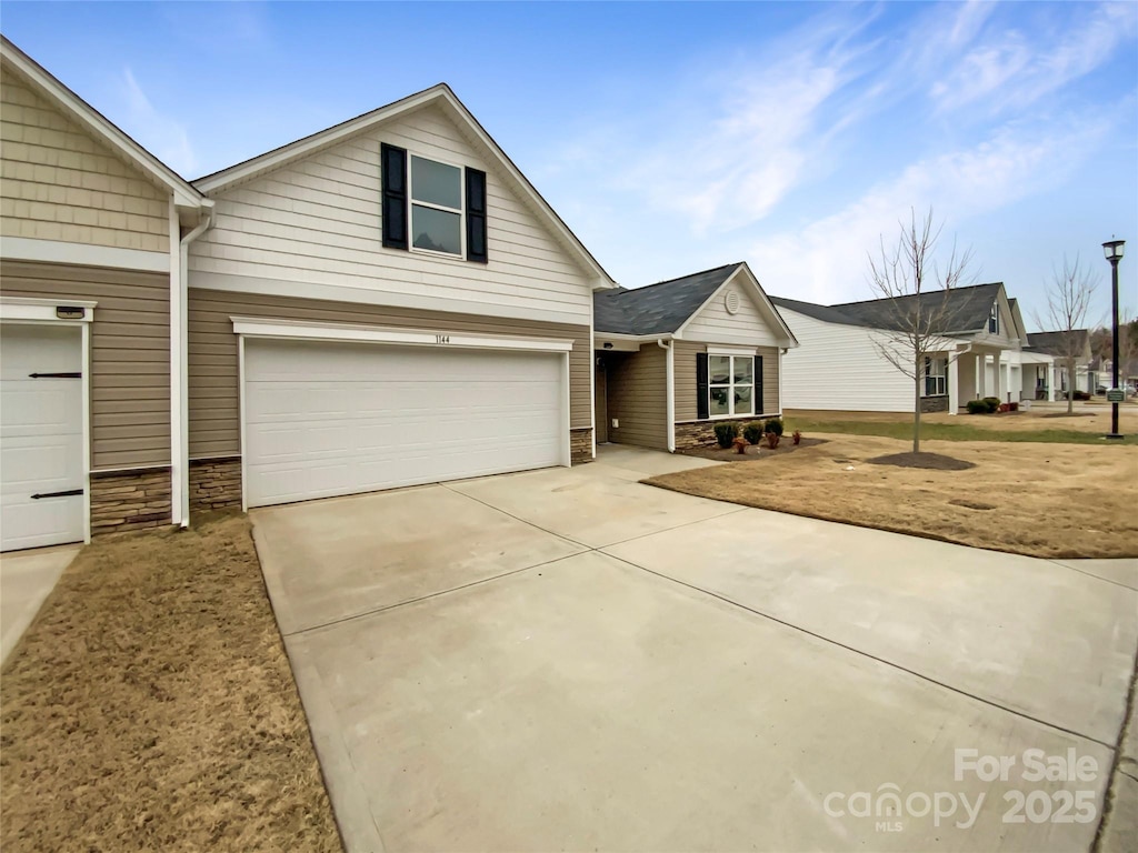 view of front of house with concrete driveway, an attached garage, and stone siding