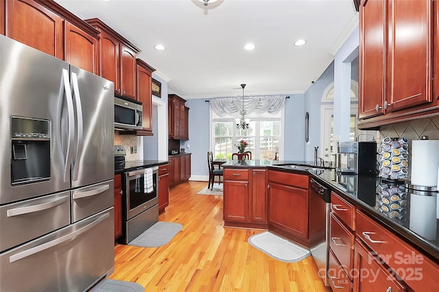 kitchen featuring light wood finished floors, crown molding, decorative backsplash, dark countertops, and stainless steel appliances
