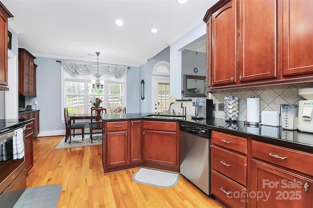kitchen featuring ornamental molding, a chandelier, decorative backsplash, light wood-style floors, and stainless steel appliances