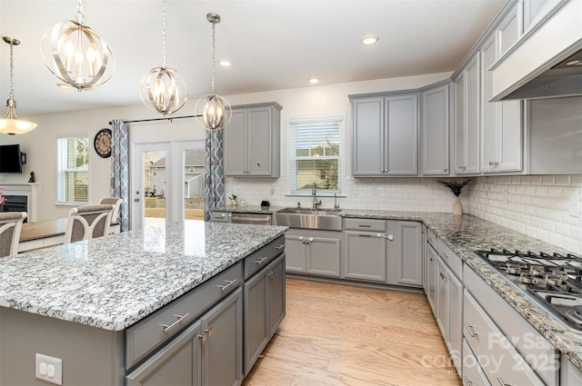 kitchen with custom range hood, an inviting chandelier, gray cabinets, stainless steel gas stovetop, and a sink
