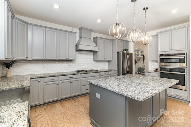 kitchen with gray cabinetry, custom exhaust hood, a chandelier, and appliances with stainless steel finishes
