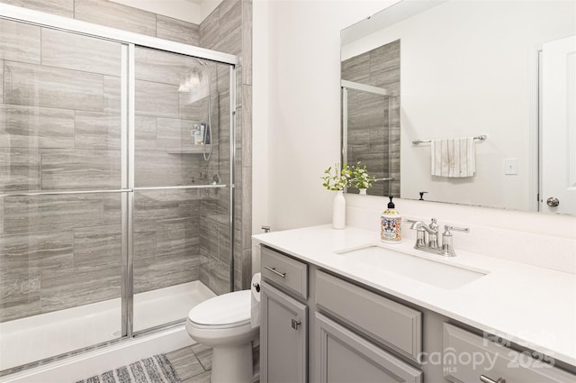 full bath featuring toilet, a shower stall, and vanity