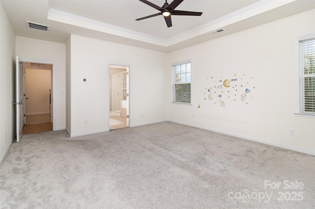 unfurnished bedroom featuring a tray ceiling, carpet flooring, and visible vents