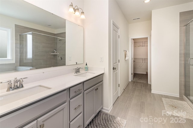 bathroom with a shower stall, double vanity, visible vents, and a sink