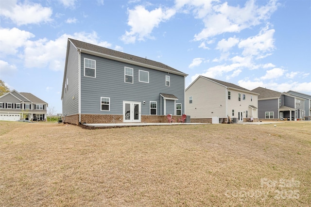 back of property with a patio, french doors, brick siding, and a yard