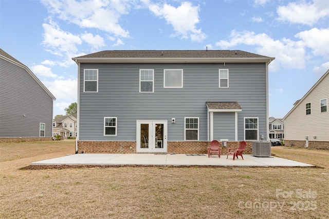 back of property with central air condition unit, a yard, a patio area, brick siding, and french doors