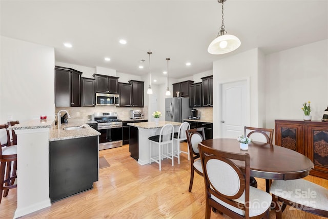 dining room with a toaster, recessed lighting, and light wood-style floors