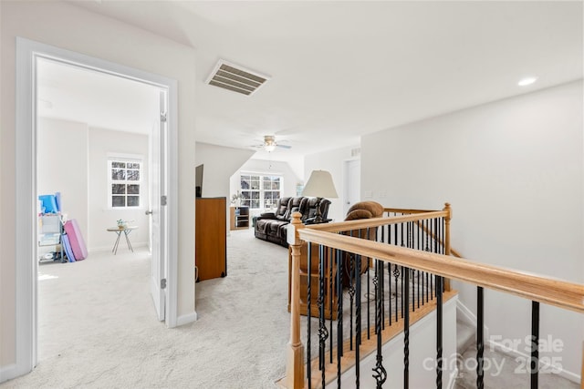 hall featuring an upstairs landing, visible vents, light colored carpet, and baseboards